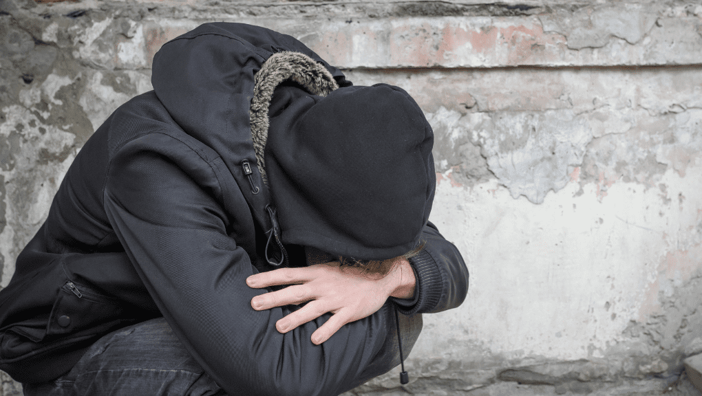 addiction (2) Man with his head in between his knees in an ally